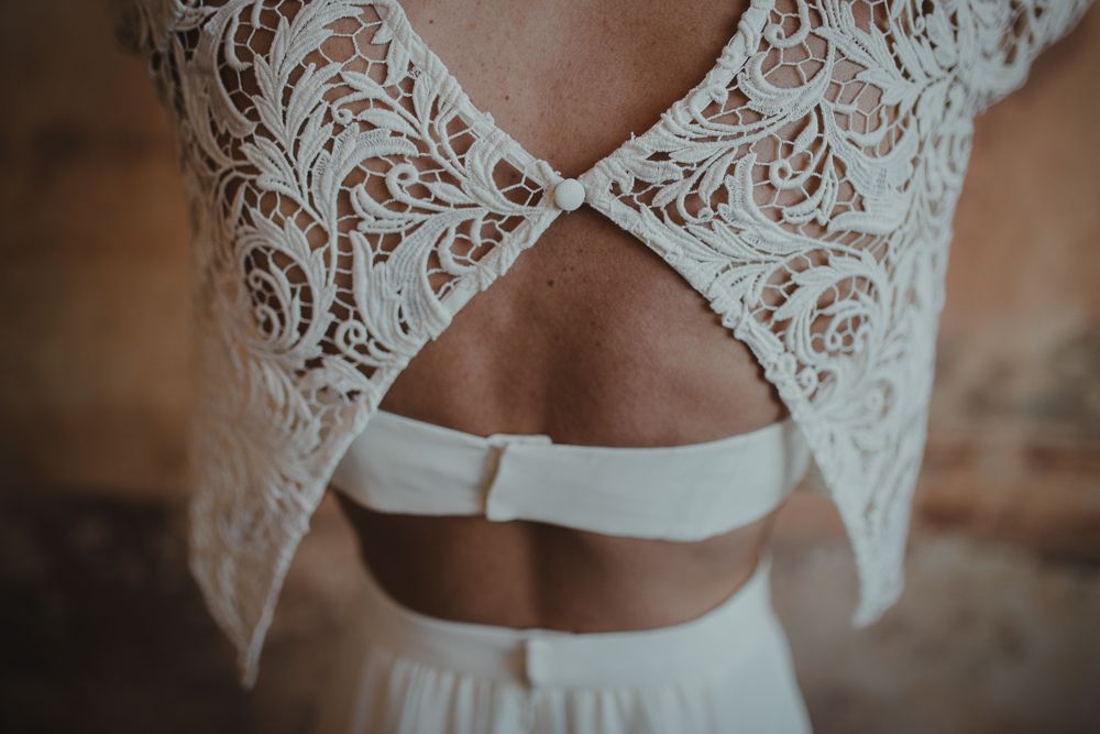 Detailed photograph of a wedding dress back featuring delicate white lace and crossed straps.