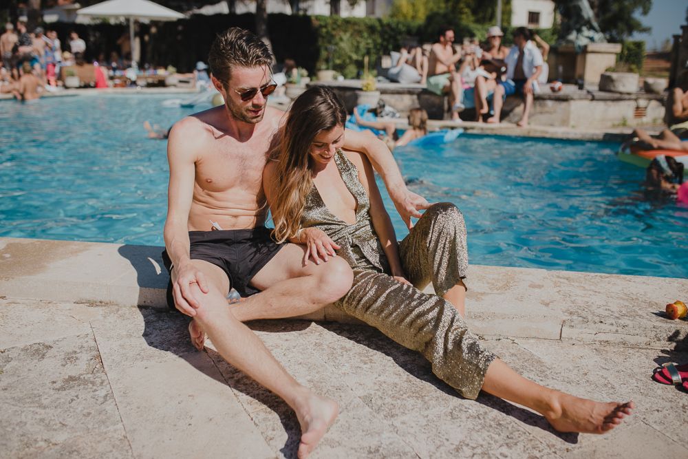 Couple relaxing by resort swimming pool on sunny afternoon.