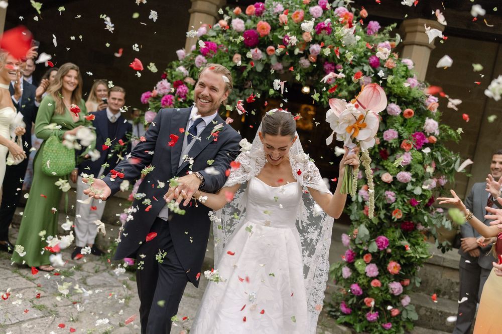 Wedding celebration with flower petals being tossed amid pink and green floral decorations.