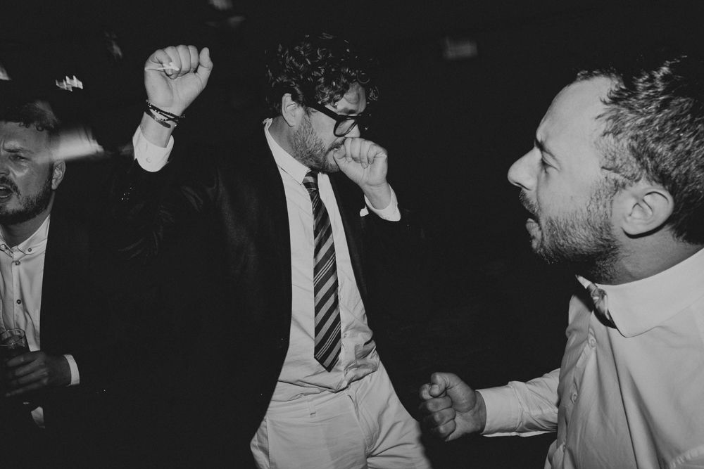 Men in formal attire dancing enthusiastically at a lively party.