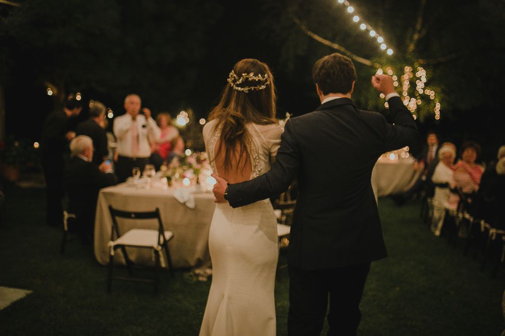 A wedding reception under string lights with guests seated at decorated tables.