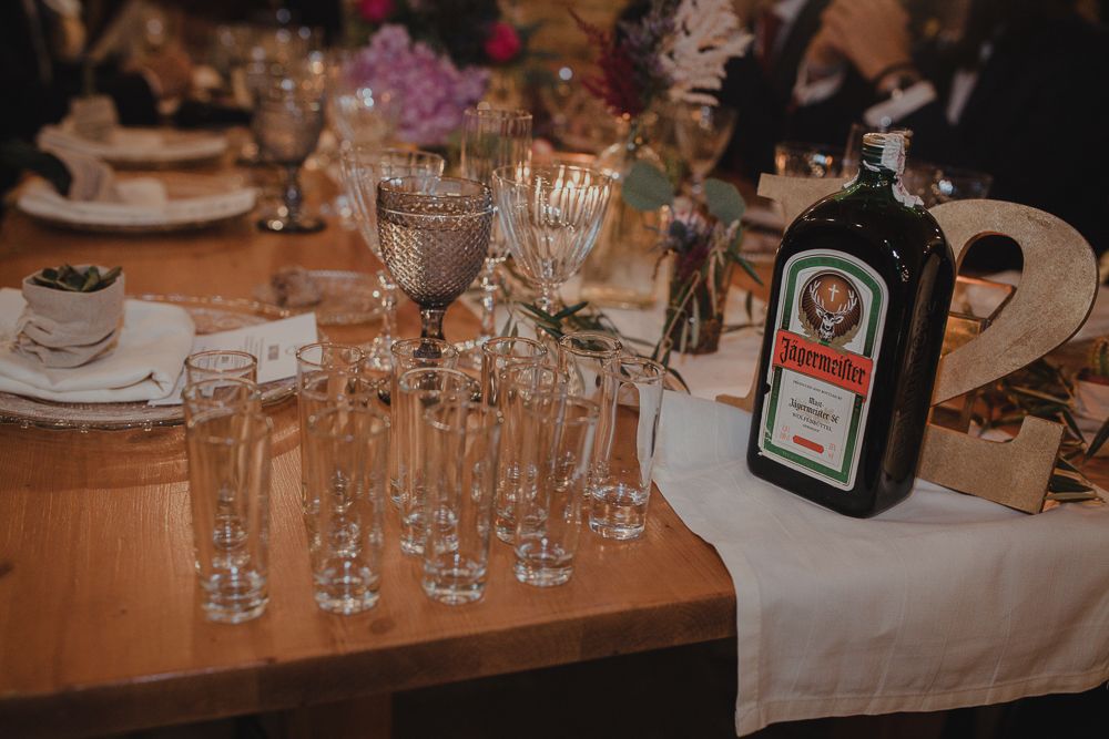 Table setting with crystal glasses and bottle of Jagermeister at event.