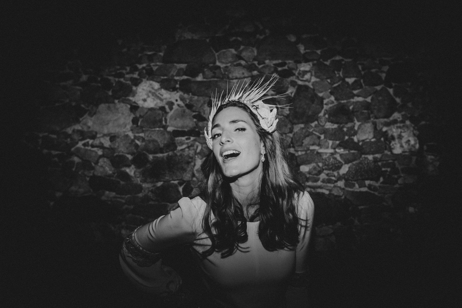 Black and white portrait of person wearing crown against brick wall background.