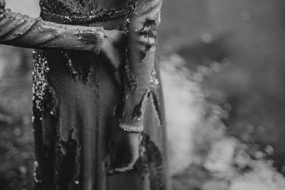 Black and white detail shot of a wet, sparkly dress in moody lighting.