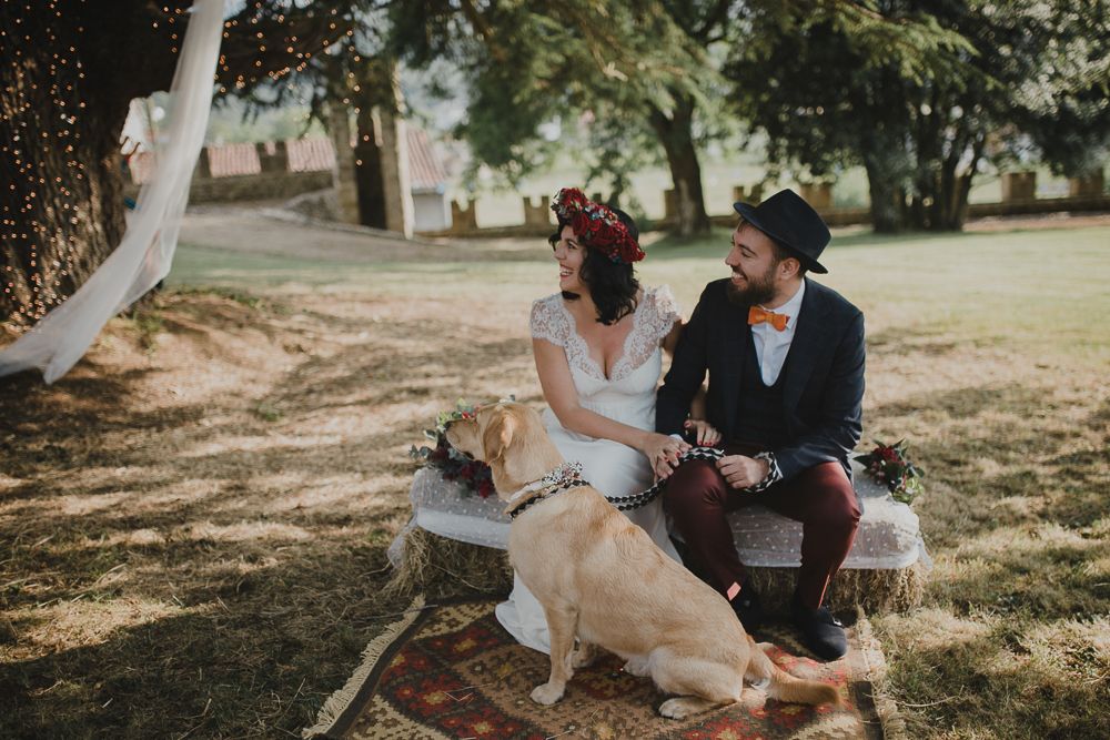Couple relaxes on bench with their dog in dappled sunlight.