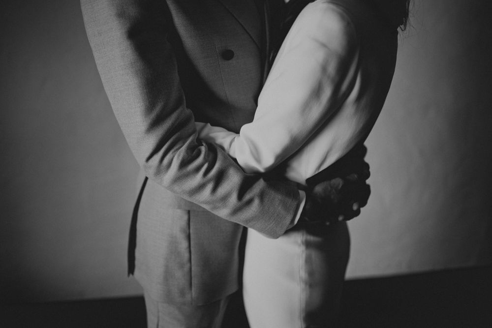 Black and white photo showing details of formal wear and gentle embrace between two people.