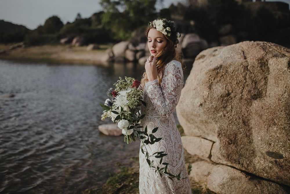 White lace gown and bouquet photographed against scenic lake and rock formations.