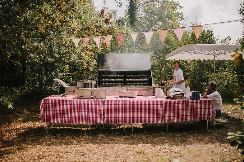 Outdoor buffet table with pink checkered tablecloth and bunting decorations.