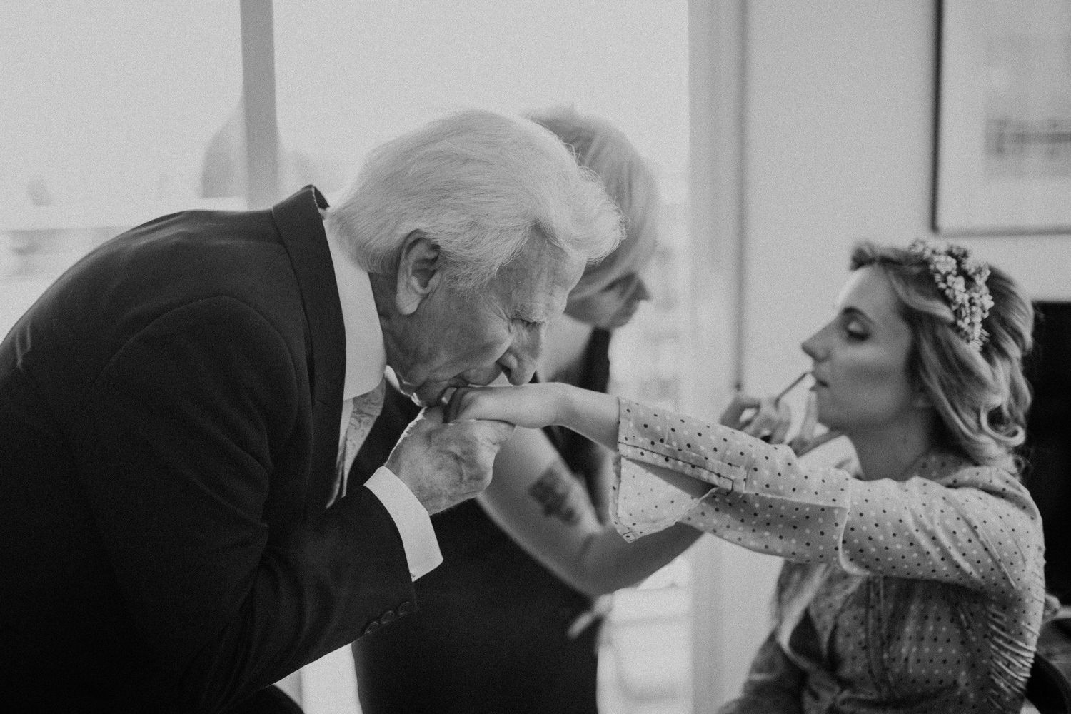 Black and white photo of a tender moment between a bride and an elderly man during a wedding ceremony.