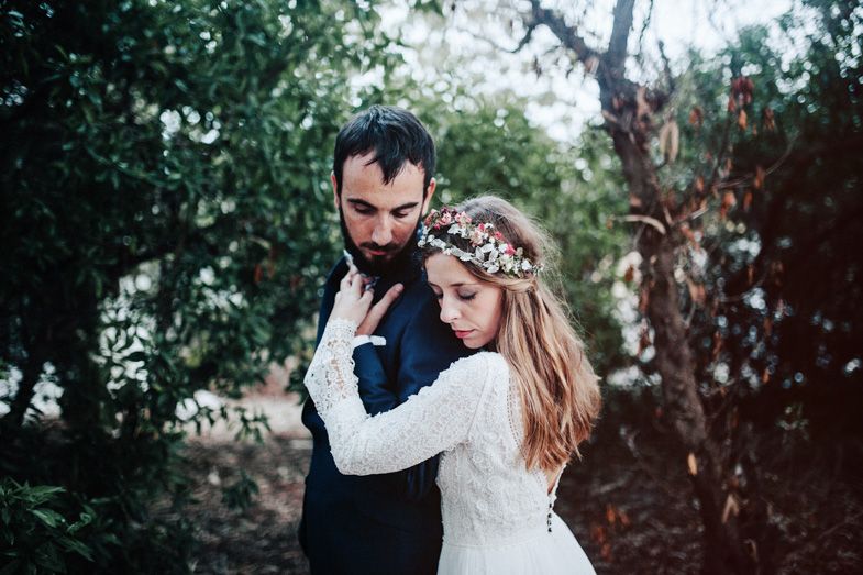 A romantic wedding couple embraces in an outdoor forest setting with soft lighting.