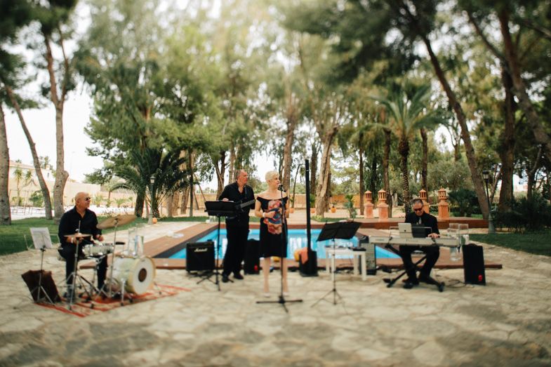 A string quartet performing outdoors among trees at a garden event.
