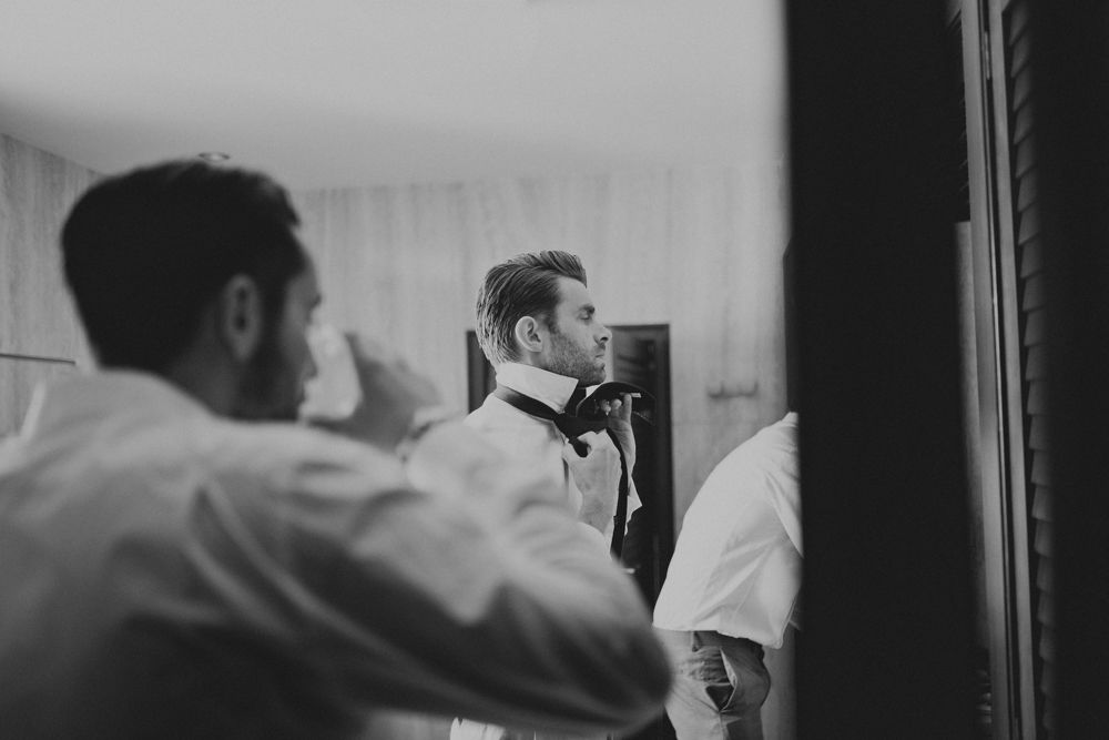 Black and white image of people getting ready in front of a mirror.