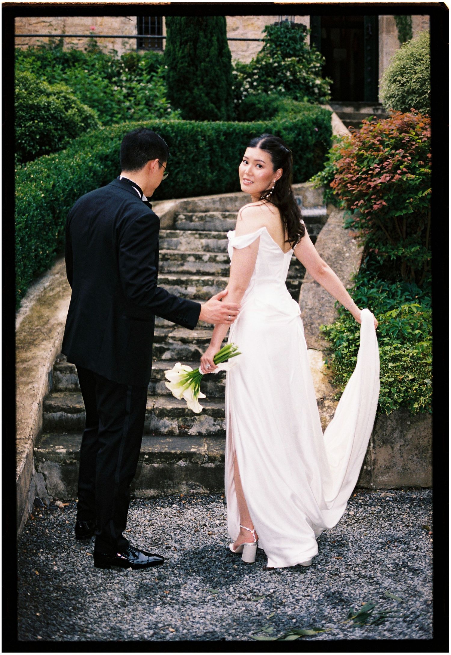 A series of romantic wedding photos showing a couple in formal attire descending stone garden steps in a lush outdoor setting.