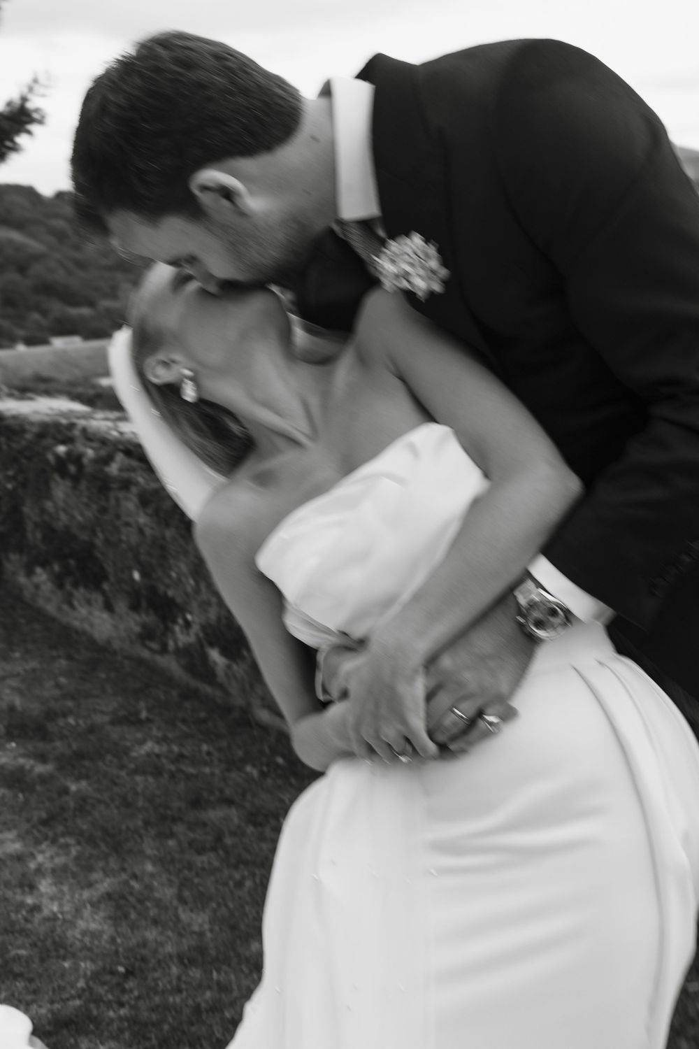 Black and white romantic wedding moment captured against a natural outdoor backdrop.