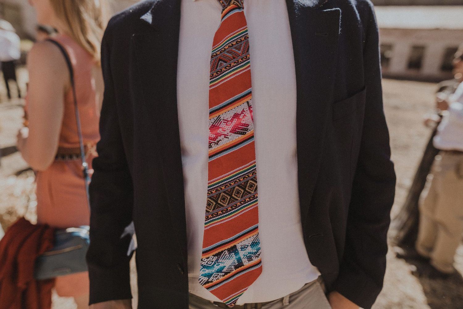 Close-up of red and white patterned tie against dark suit jacket.