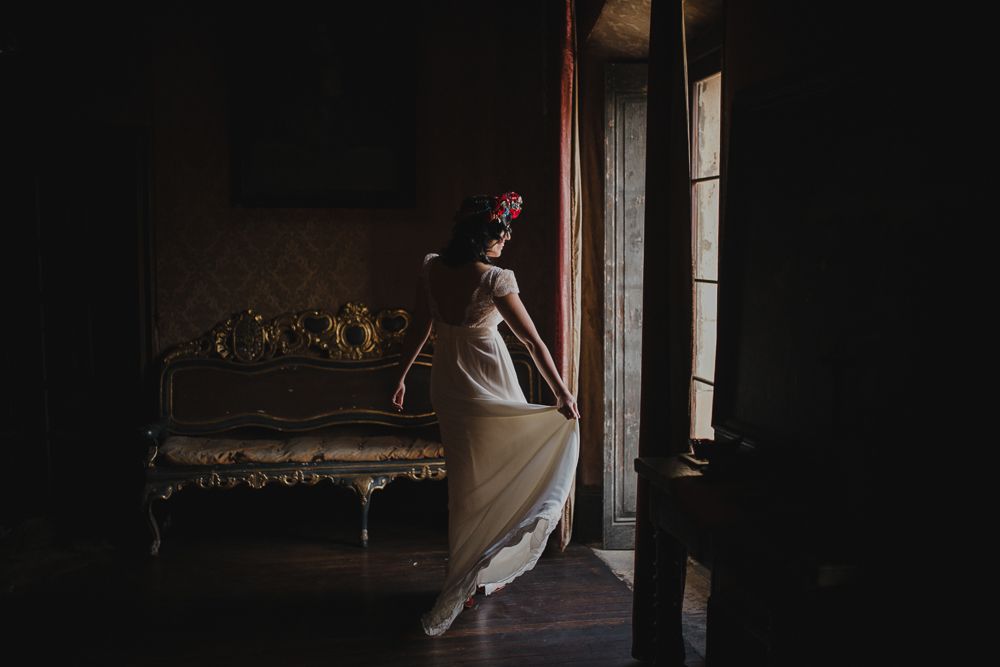 Elegant dancer in white dress twirls near antique furniture in dark room.