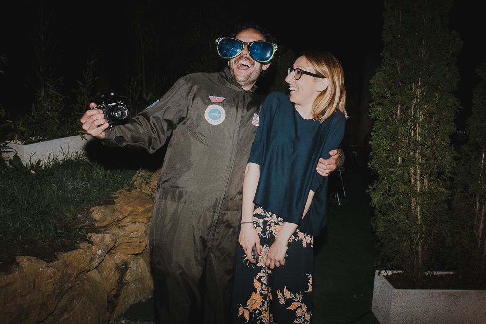 Two people pose playfully at a nighttime party wearing festive attire and accessories.