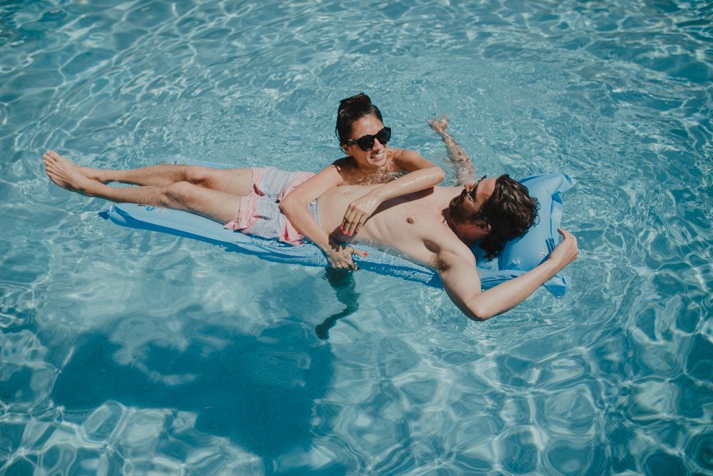 Person floating relaxed on pool float in clear blue swimming pool water.