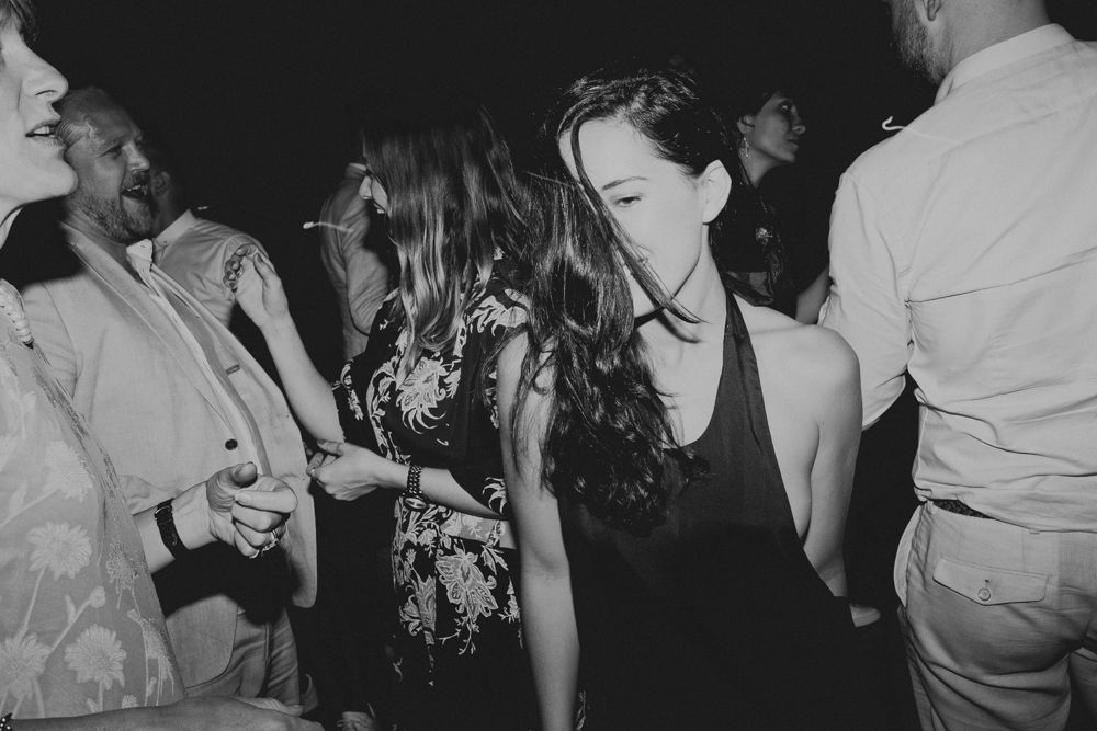 Party guests dance and celebrate at a dimly lit indoor event.