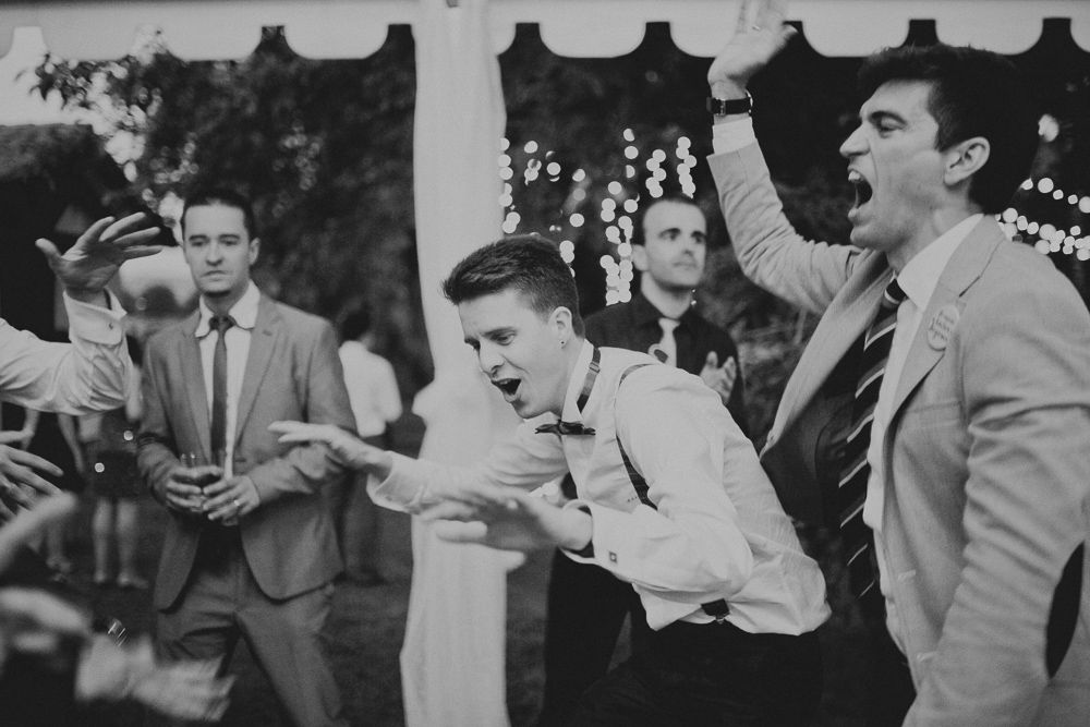 Vintage black and white photo of wedding guests having an animated reaction at a reception.