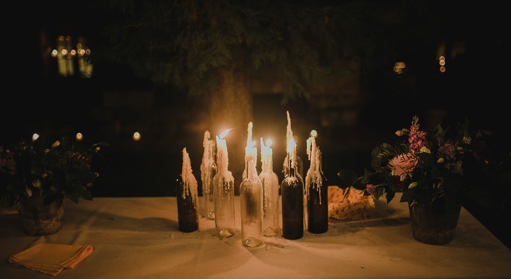 Multiple lit candles in glass holders create a romantic centerpiece on a dark table.