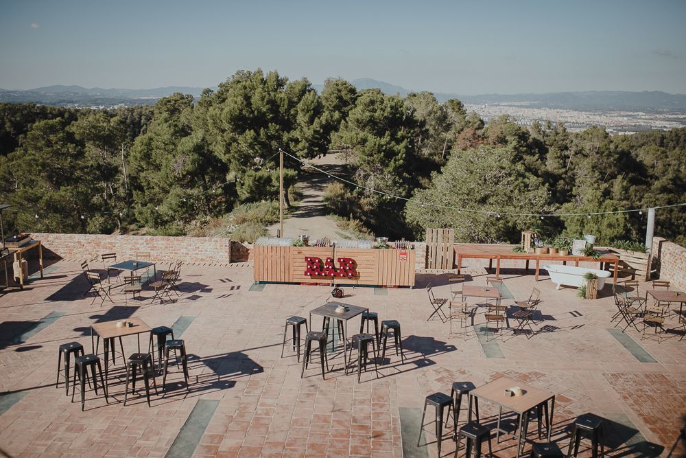 An outdoor venue setup with metal stools and tables overlooking a mountain landscape.