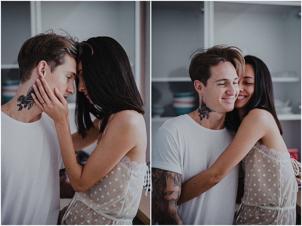 Intimate couple sharing tender moments in a kitchen with soft lighting and modern decor.