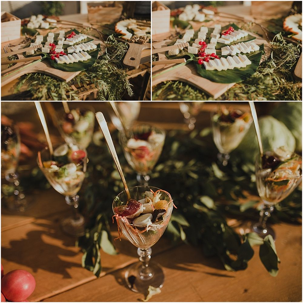 Decorated cocktail glasses with floral garnishes and greenery on wooden surface.
