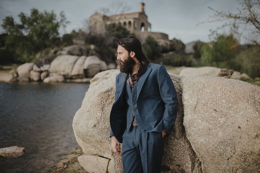 Rugged cliffs and an old stone building create a dramatic backdrop at a lakeside location.