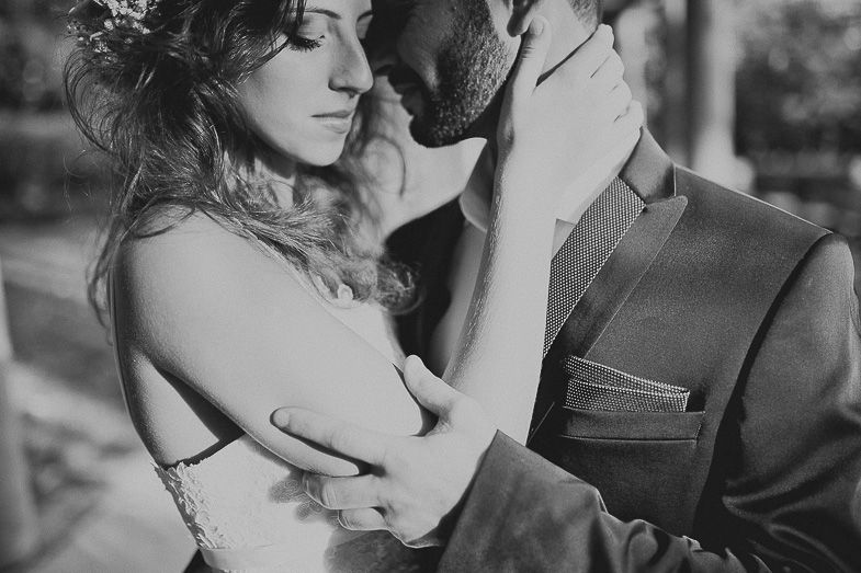 A romantic black and white portrait of an intimate couple embracing in formal attire.
