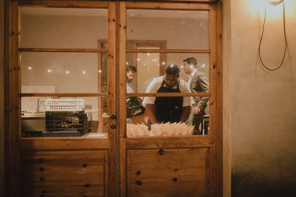 View through wooden window frame of restaurant interior with warm lighting.