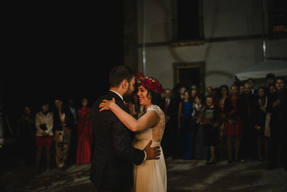 A tender moment during a wedding dance with guests watching in the background.