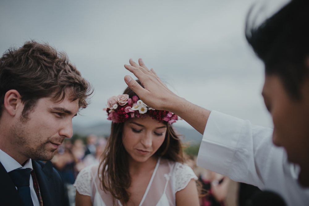 A blessing is given during an outdoor wedding ceremony with mountains visible in the distance.
