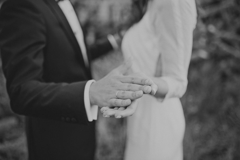 Close-up of hands showing wedding rings during an outdoor ceremony.