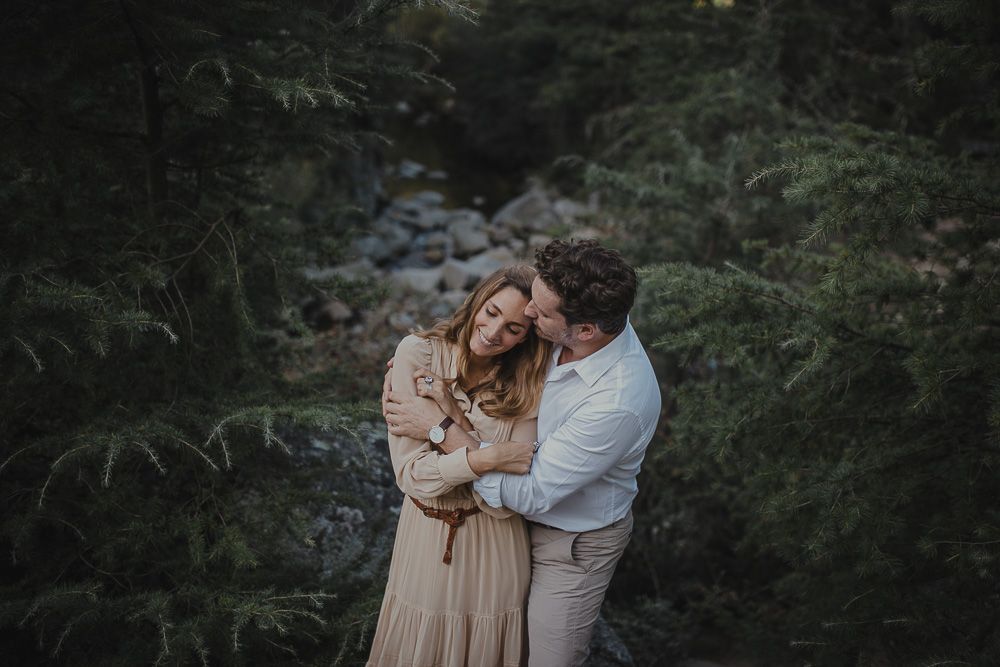 An intimate embrace photographed in a lush forest setting.