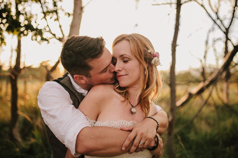An intimate wedding portrait taken during golden hour in a natural setting.