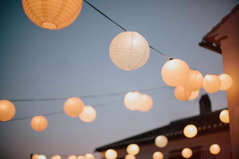 String of illuminated paper lanterns glowing against dusky blue sky.