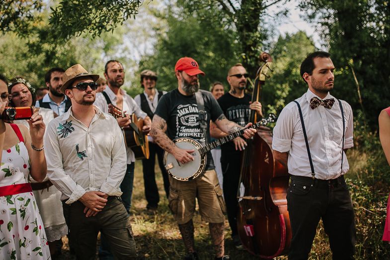 Wedding band with instruments performs outdoors for guests.