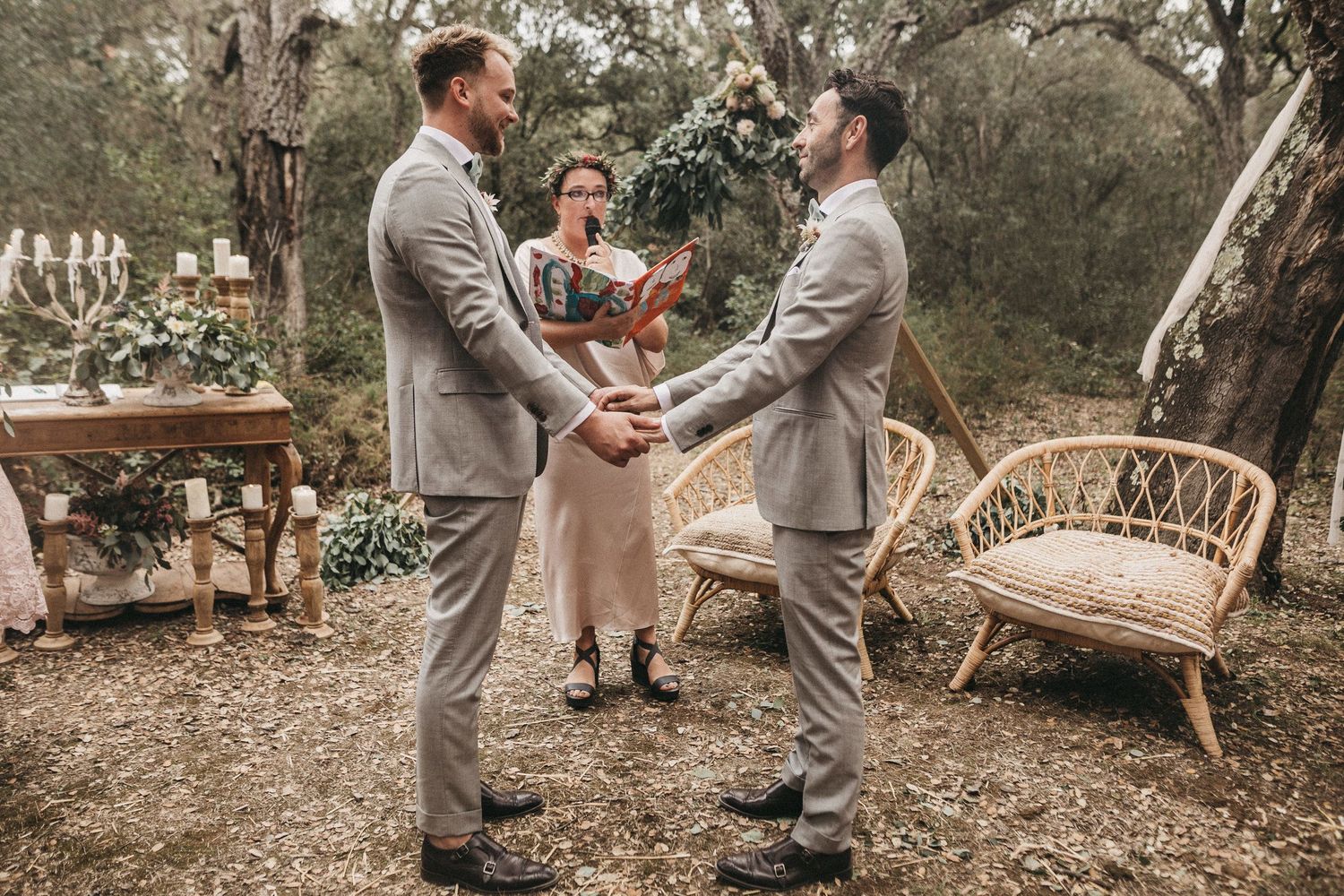 Outdoor garden wedding ceremony with wicker furniture and natural decor.