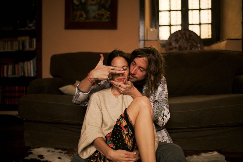 Playful moment captured on a couch in a living room with warm lighting.