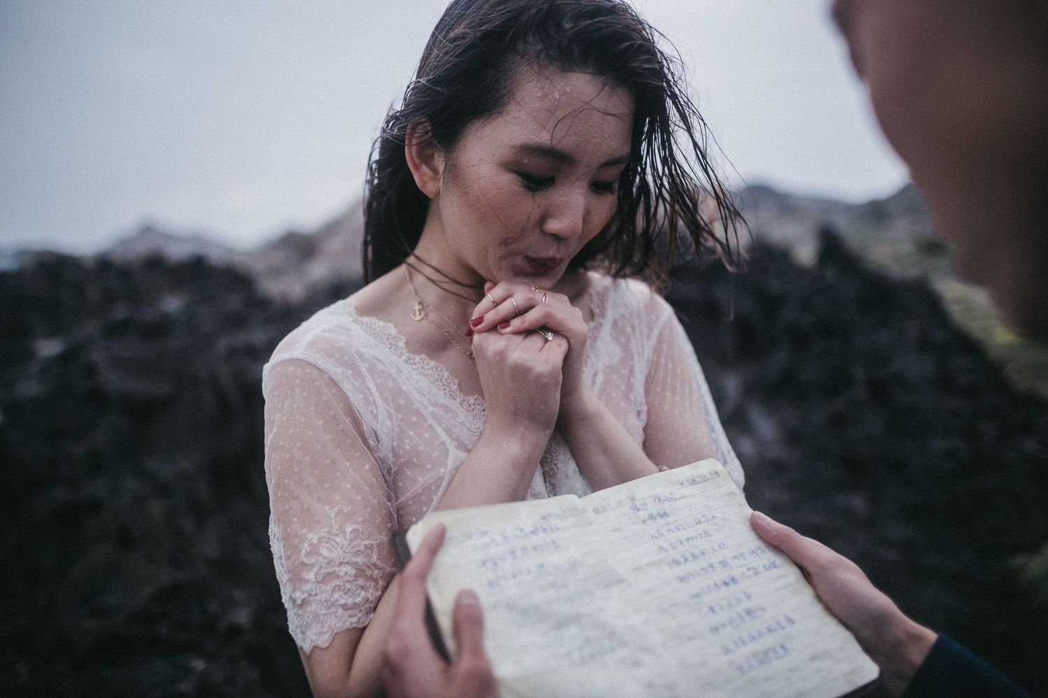 A woman in white lace reads an emotional letter outdoors.