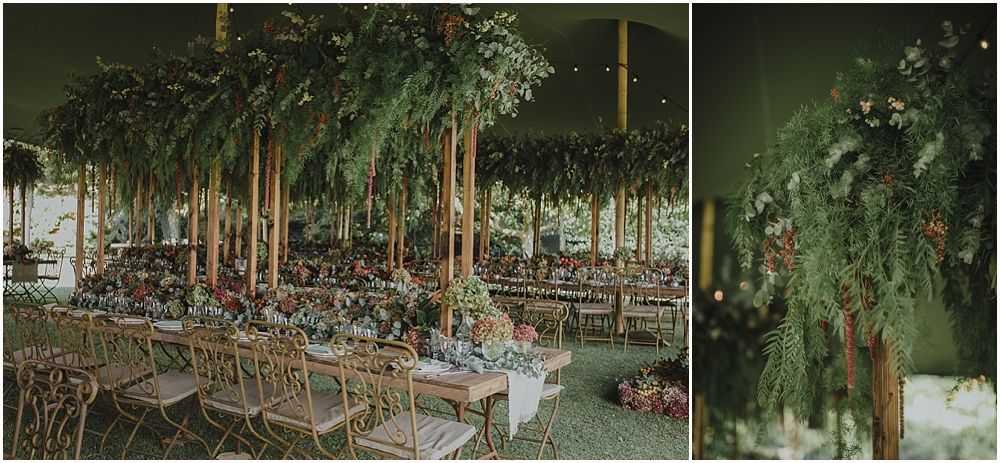 Forest-themed wedding reception venue with hanging greenery and wooden chairs.