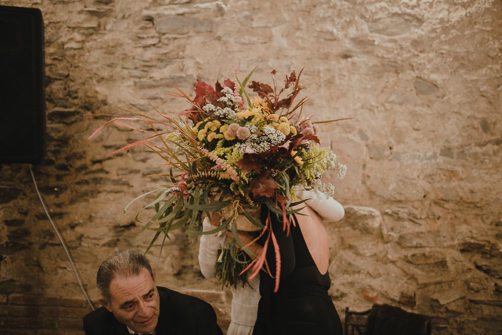 Group photo of wedding guests posing with fun props against brick wall.