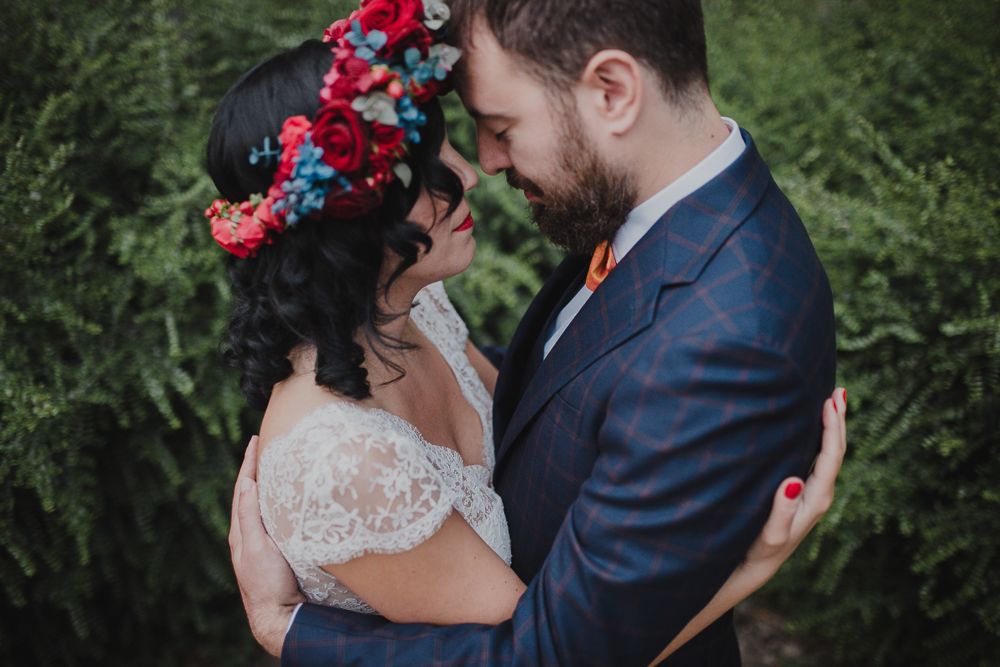 An intimate moment between newlyweds with the bride wearing a stunning red floral crown.