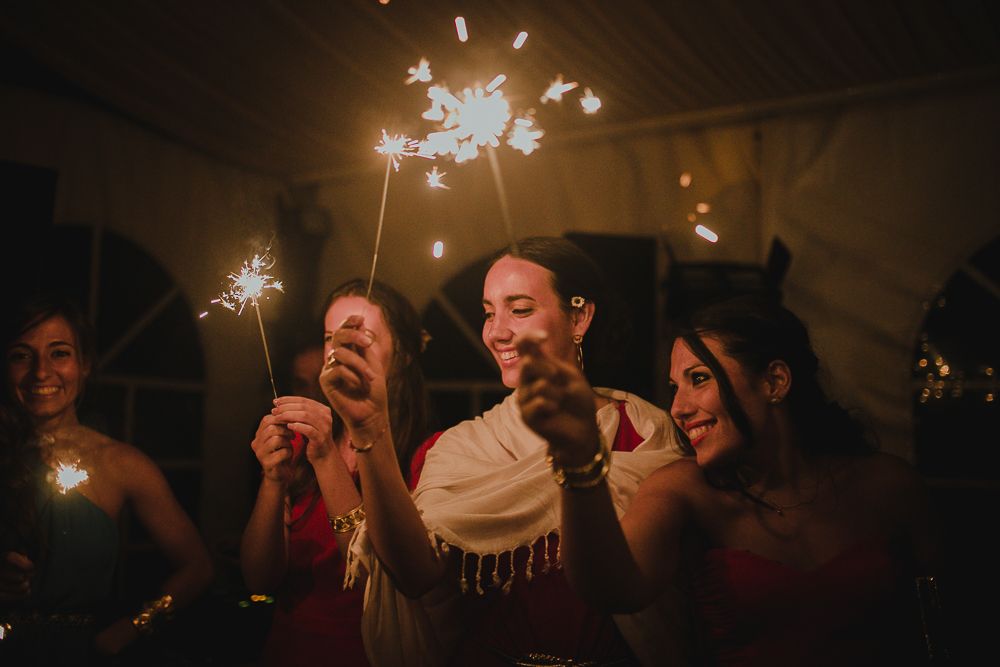 Wedding guests celebrate with sparklers creating a joyful nighttime moment.