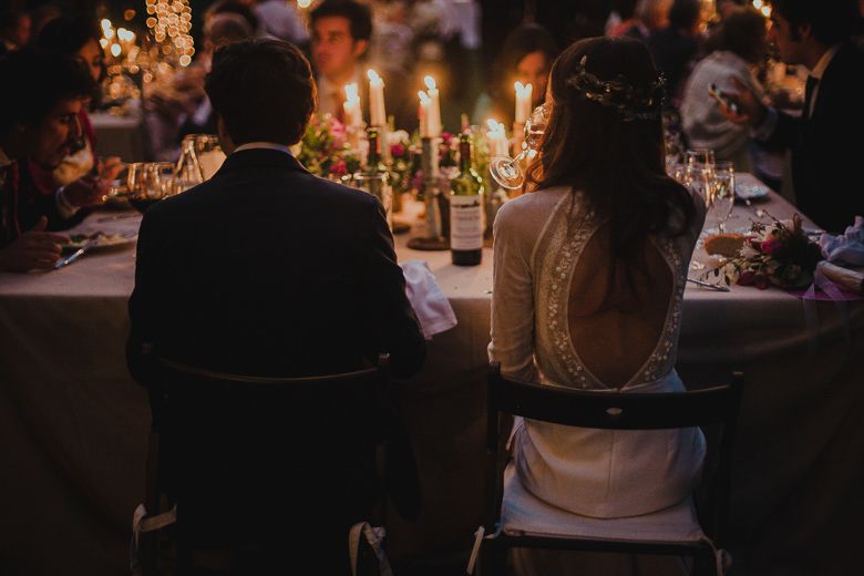 Candlelit wedding reception dinner with couple seated at table with glowing ambiance.