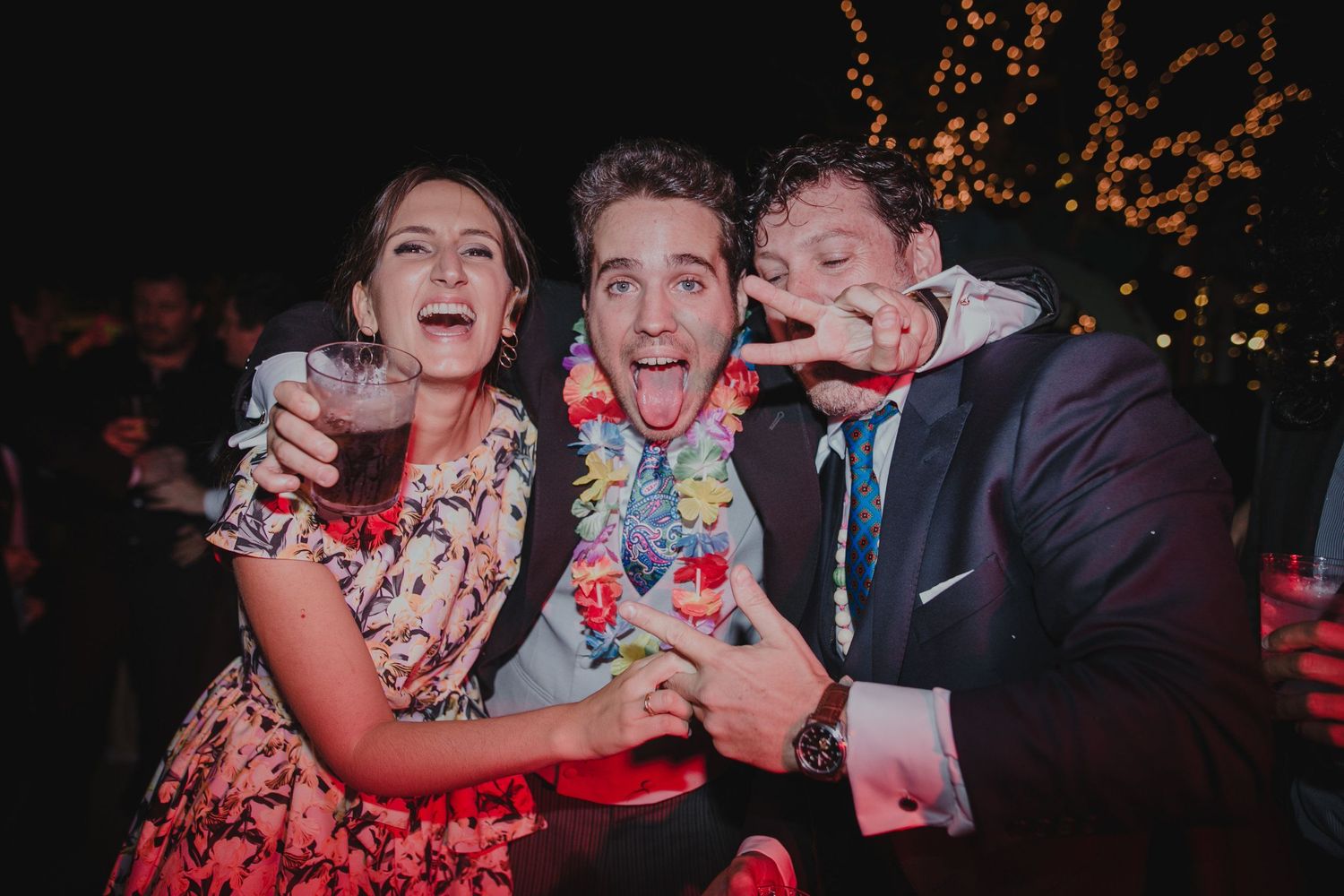 Wedding reception guests sharing colorful drinks and laughing together.