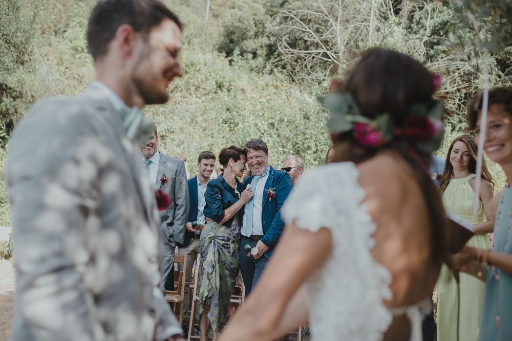 Wedding ceremony in garden setting with guests watching as bubbles float through the air.