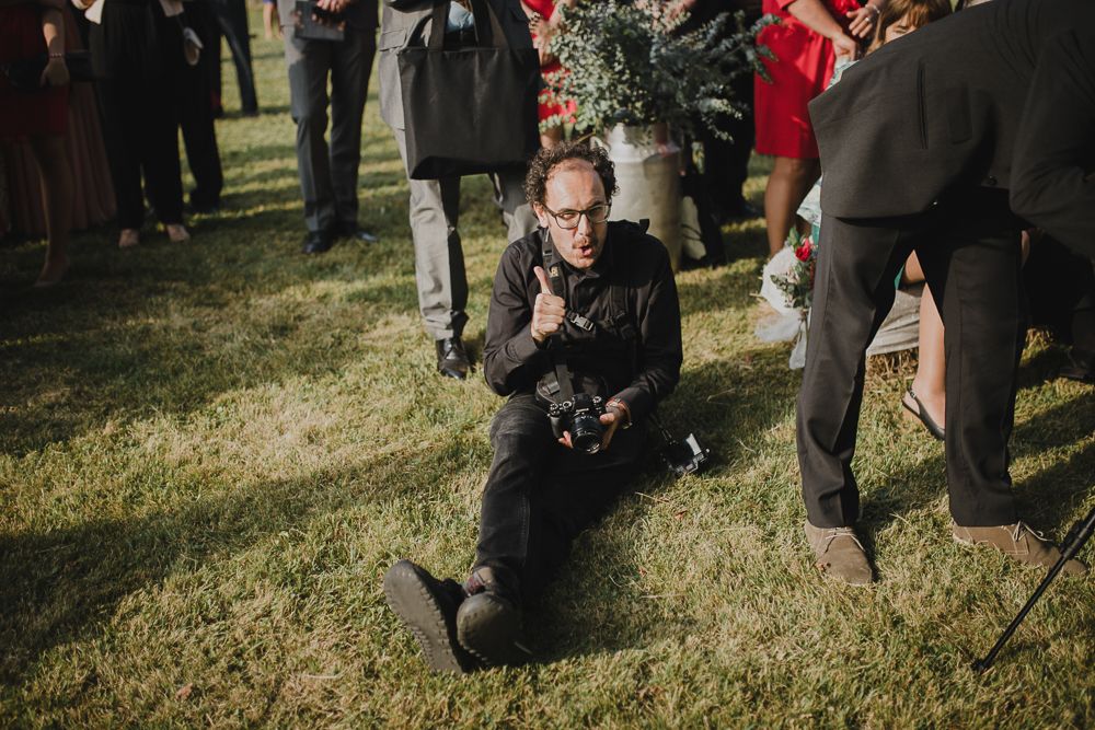A photographer kneels on grass to capture shots during an outdoor event.