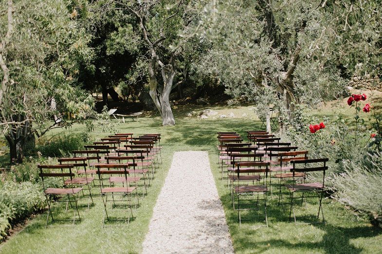 Outdoor wedding ceremony setup with wooden chairs arranged in rows along a garden path.